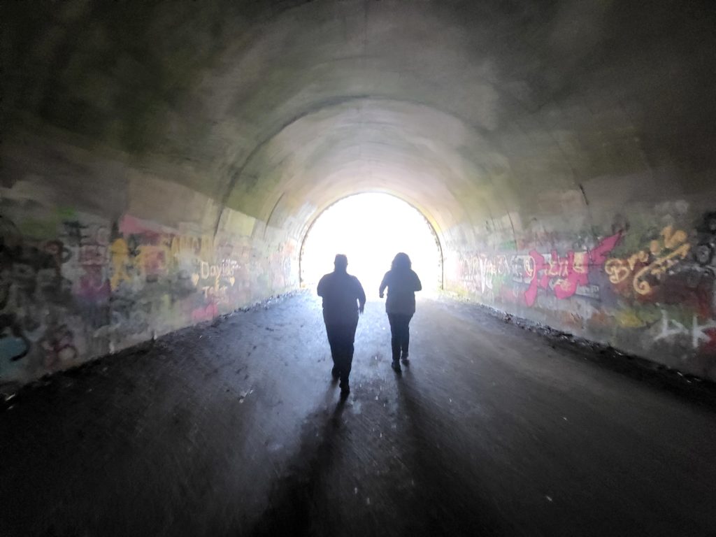 Two people walking through the Road to Nowhere Tunnel